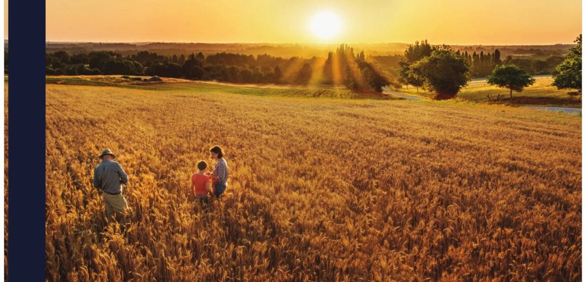 A farm family standing in a wheat field at sunset